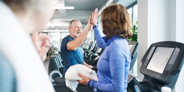 Elderly Man and Woman High-Fiving on Treadmills at an Independent Living Facility